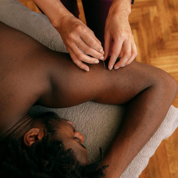 A Woman Inserting a Needle Lying on a Man's Arm